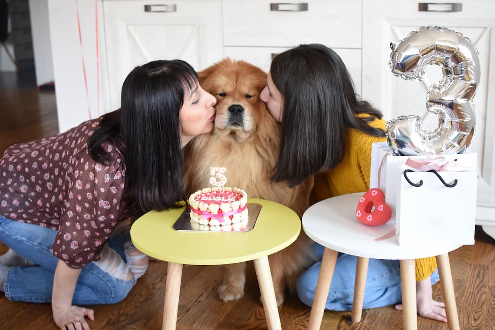 two women kissing their dog for birthday